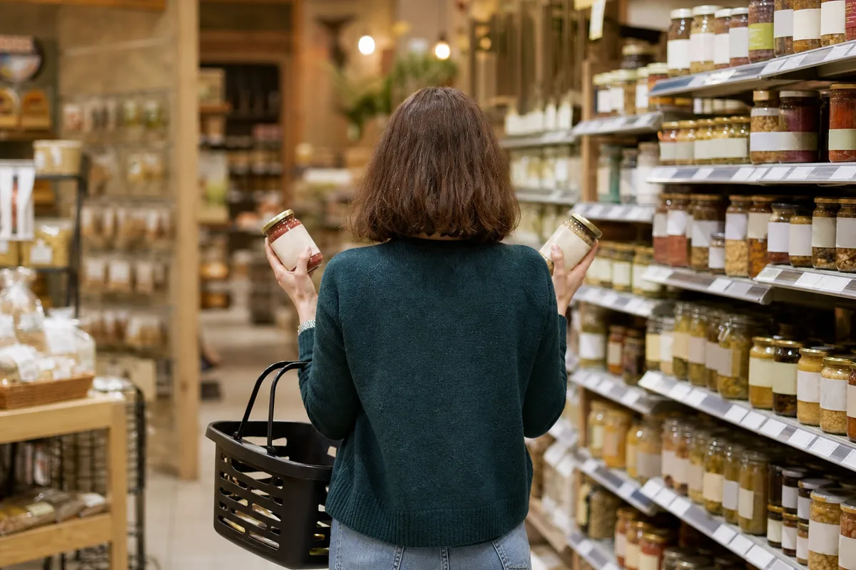 Cliente vue de dos comparant deux produits dans un rayon d&rsquo;épicerie bio